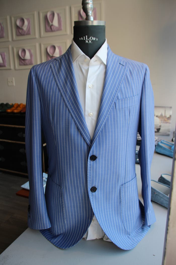 Stylish blue pinstripe suit showcased on a mannequin in a tailor's studio.
